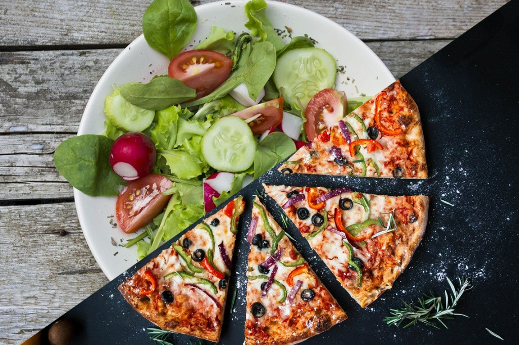 Ein Teller auf der einen Seite ein Salat auf der anderen eine Pizza.