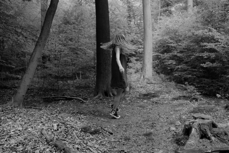 Eine junge Frau steht im Wald und dreht sich