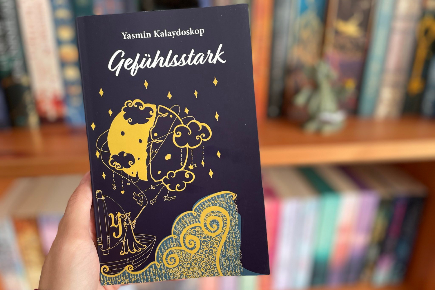 Buch Gefühlsstark vor einem Bücherregal